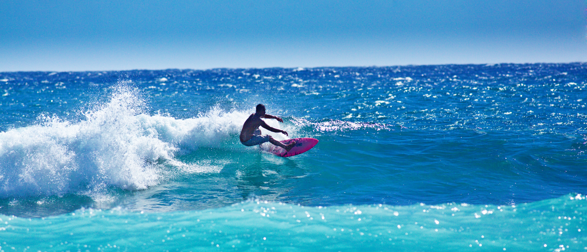 A local Hawaiian surfer surfing at Poipu Beach, Kauai, Hawaii.